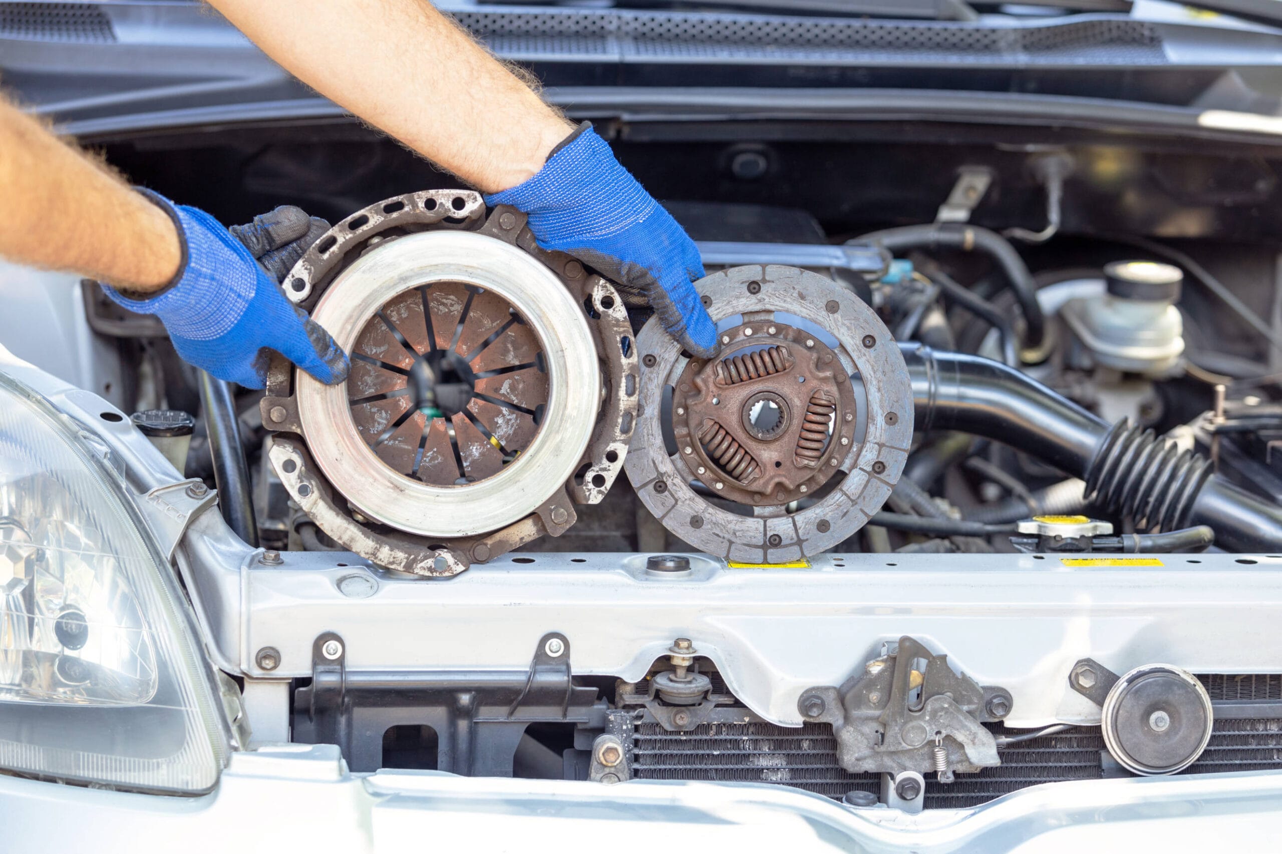 "Mechanic holding worn clutch pressure plate and disc during transmission repair service"